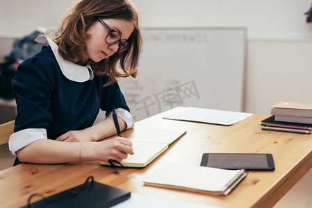 魔法少女小樱摄影照片_学校的女孩写在笔记本上坐在桌子功课, 家庭作业