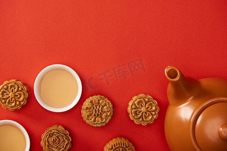 在红色上隔离的传统月饼、茶壶和杯子的顶视图