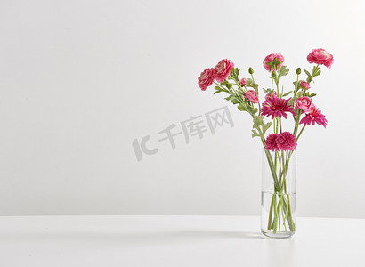 闪光花字摄影照片_白色壁纸后面的花瓶中的花