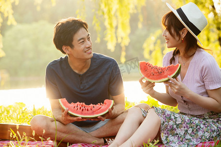 夏天坐在草地上吃西瓜的幸福情侣