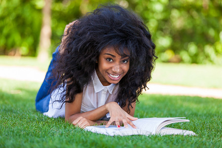 年轻的学生女孩读一书在学校公园-非洲 p