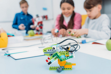 五颜六色的手工机器人在办公桌与学童在茎类的背景