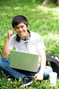 亚洲帅哥摄影照片_在公园的笔记本电脑与亚洲年轻帅哥