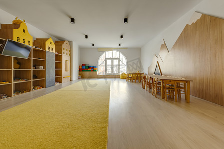 cozy kindergarten classroom interior with yellow carpet, tables and tv