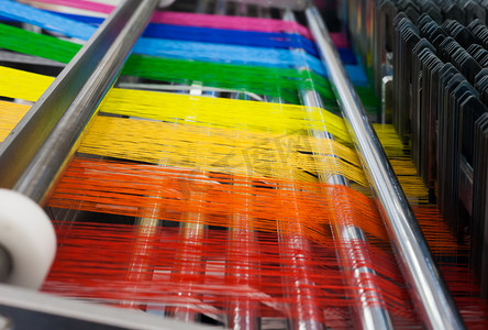 fabric摄影照片_Textile machine with rainbow colors threads