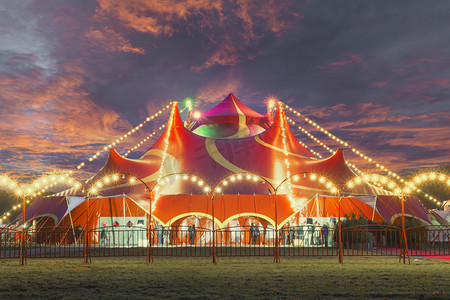 Night view of a circus tent under a warn sunset and chaotic sky