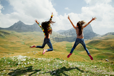 panoramic摄影照片_two girls happy jump in mountains with exciting view