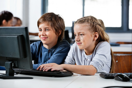 男孩和女孩在学校的计算机实验室中使用桌面 pc