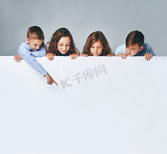 四孩子拿着一个大广告牌, 看着它.