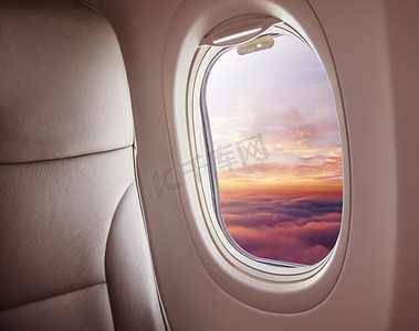 飞机空中摄影照片_飞机内部与窗口视图日落在云彩之上。旅行和空运概念