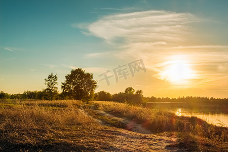 春天田野阳光摄影照片_景观与道附近一条河的田野。日落