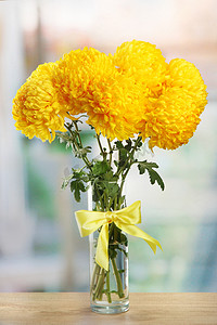 在木桌上的玻璃花瓶明亮黄色菊花