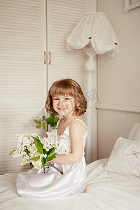 一个小女孩在一张床，一束白色的小睡衣