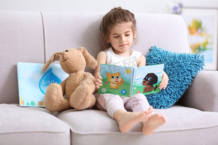 儿童沙发摄影照片_有趣的小女孩看书  