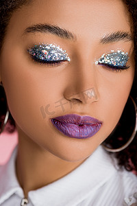 african american girl with silver glitter eyeshadows on closed eyes and purple lips, isolated on pink