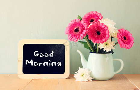 早上好摄影照片_黑板上用句早上好写在它旁边用鲜花的花瓶