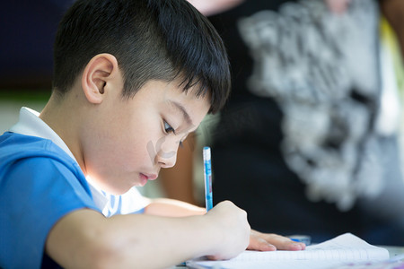 椅子免扣摄影照片_年轻的亚洲男孩做作业