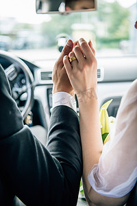 爱车摄影照片_新郎和新娘在车里手牵手的裁剪视图 