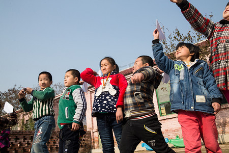 亚洲男孩摄影照片_乡村小学生在学校放纸飞机