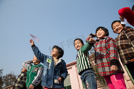 放飞机男孩摄影照片_乡村小学生在学校放纸飞机