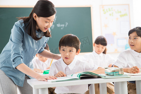 写字桌子摄影照片_老师和小学生们在教室里