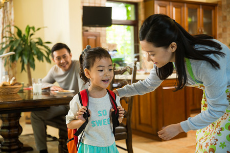 年轻亚洲家庭摄影照片_妈妈给女儿整理书包