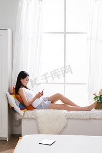 枕头侧面摄影照片_青年女人在卧室用手机