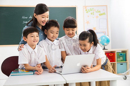 教室上课摄影照片_教师和小学生在教室里使用电脑