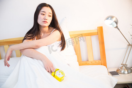 亚健康摄影照片_情绪低落的青年女人在卧室的床上