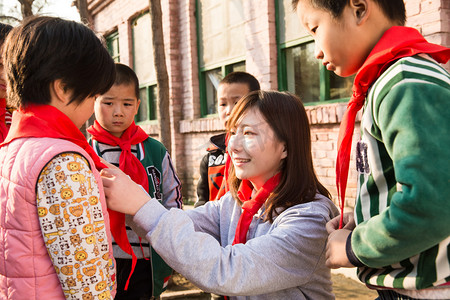 红领巾奖争章摄影照片_乡村教师和小学生在学校里