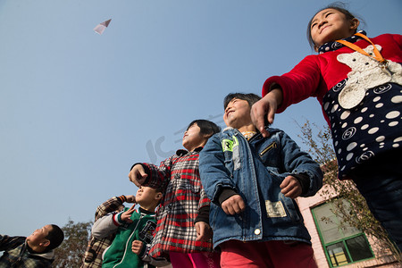放飞机男孩摄影照片_乡村小学生在学校放纸飞机