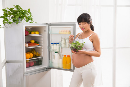 水果摄影照片_孕妇打开冰箱拿蔬菜