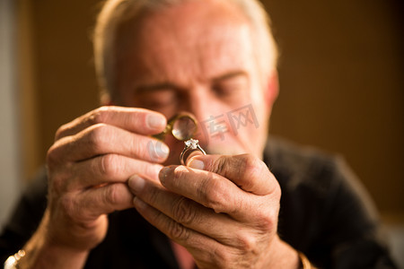 彩色钻石装饰摄影照片_老年男人拿着钻石戒指
