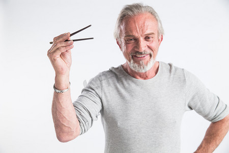 有趣图片摄影照片_老年男人拿着筷子