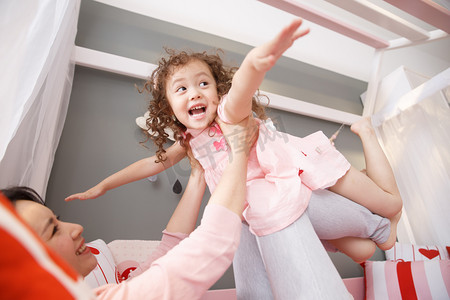 妈妈粉色摄影照片_可爱的小女孩和妈妈在卧室玩耍