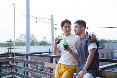 户外喝啤酒摄影照片_两个青年人喝啤酒