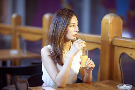 吸管拉伸效果摄影照片_青年女人在喝果汁