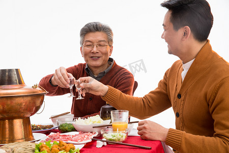 节日餐桌摄影照片_父子俩吃年夜饭喝酒