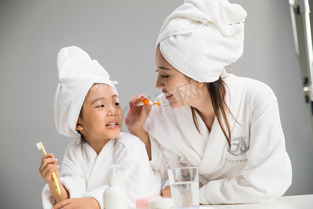 家庭刷牙摄影照片_穿着浴袍的母女刷牙