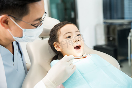 口腔器械摄影照片_男牙医在为小女孩检查牙齿