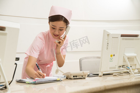 电话服务图片摄影照片_年轻女护士在接待处