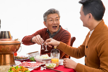 喝酒聚会摄影照片_父子俩吃年夜饭喝酒