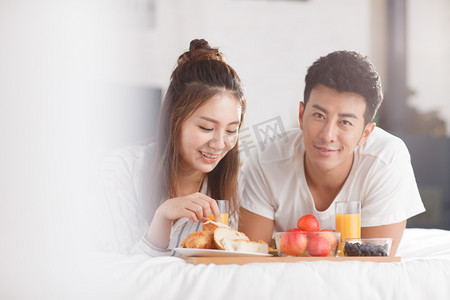 七夕节快乐字体摄影照片_青年情侣在床上吃早餐