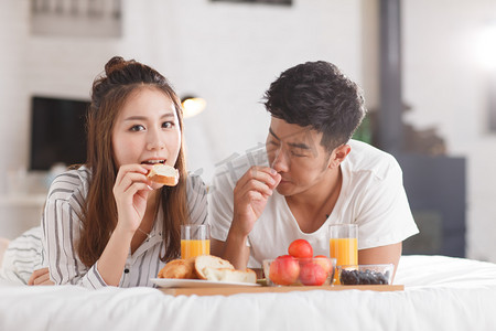 七夕简约浪漫摄影照片_青年情侣在床上吃早餐