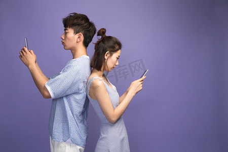 青年伴侣摄影照片_各自玩手机的青年情侣