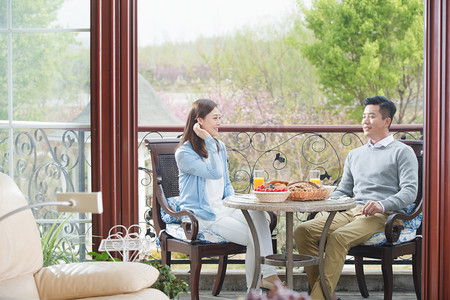 庭院栏杆摄影照片_中年夫妇在阳台上吃早餐