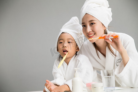 家庭刷牙摄影照片_穿着浴袍的母女刷牙