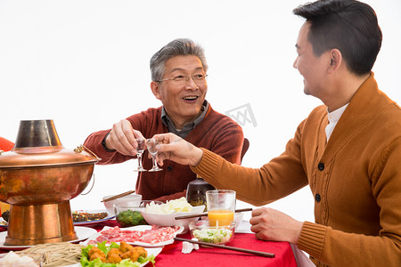 老年人喝酒摄影照片_父子俩吃年夜饭喝酒