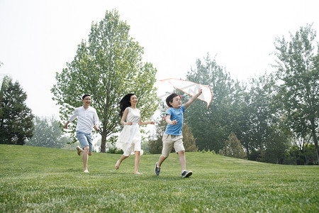 风筝摄影照片_一家三口在草地上奔跑