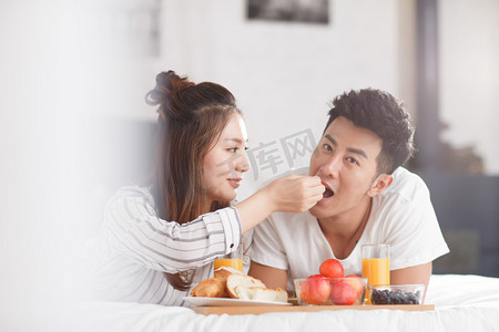 清新简约彩色摄影照片_青年情侣在床上吃早餐